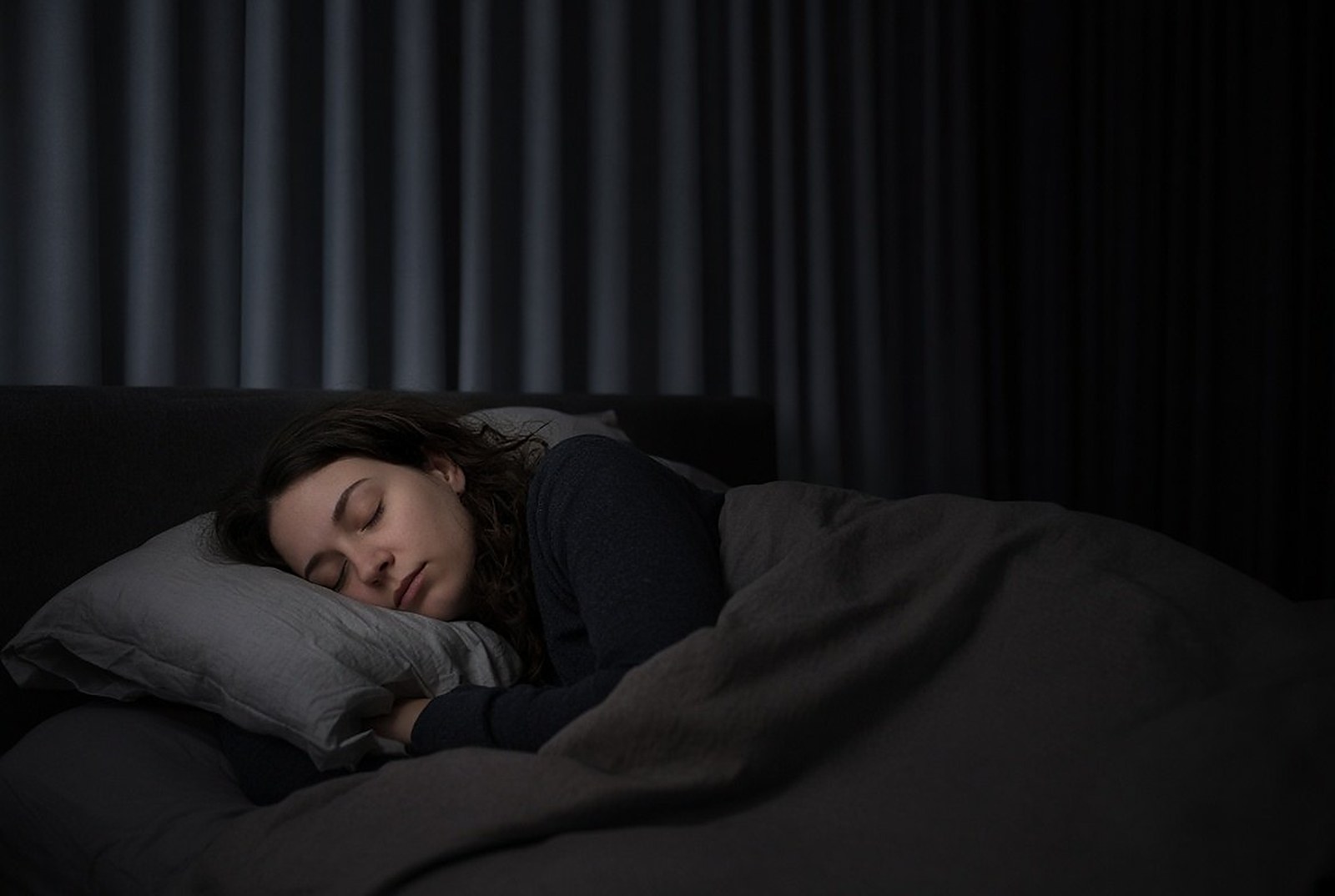 Jonge vrouw slaapt overdag in een verduisterde slaapkamer na een nacht werken, slaap bij nachtwerk